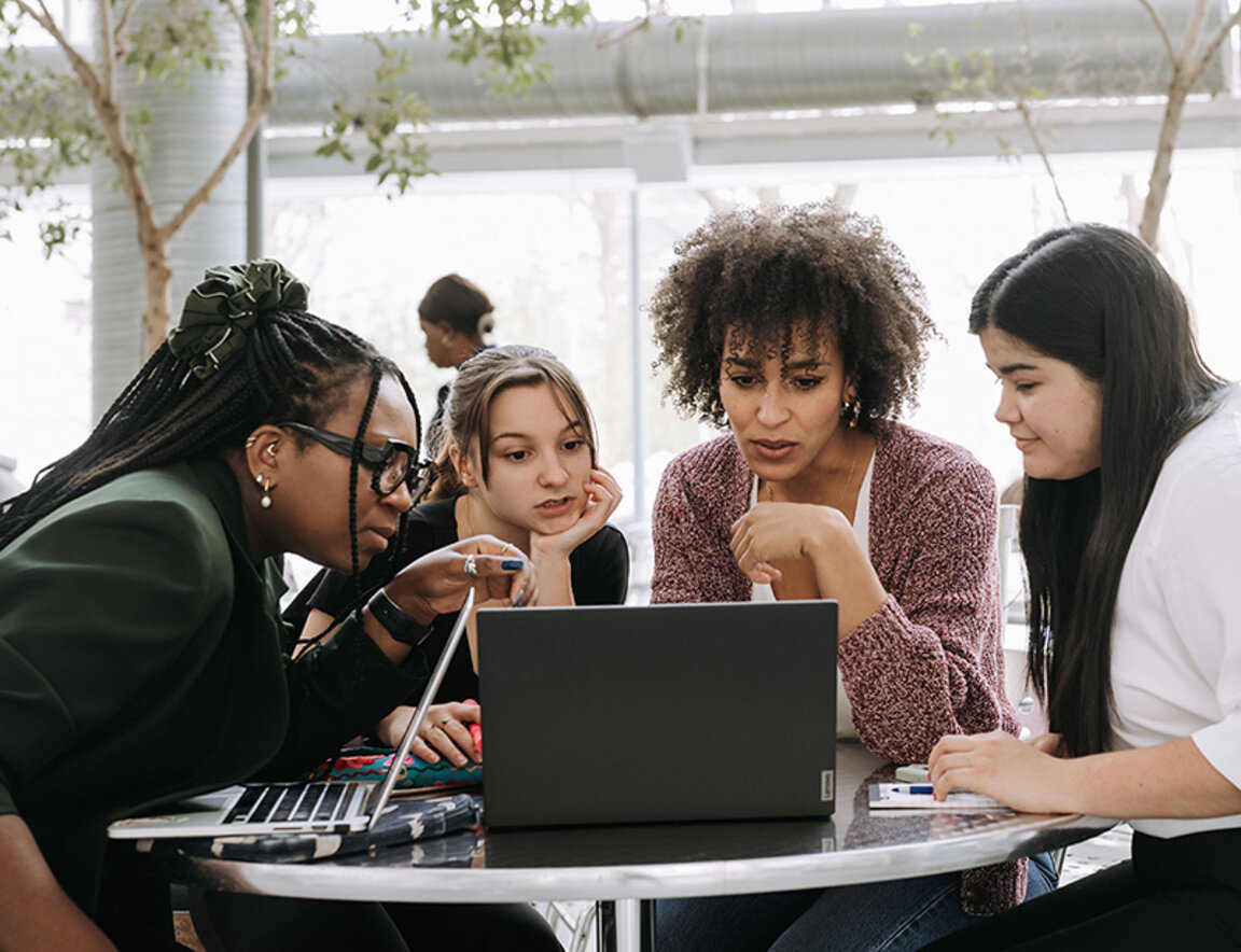 A group of students chatting and working together around a laptop in a common area at HEC Montréal.