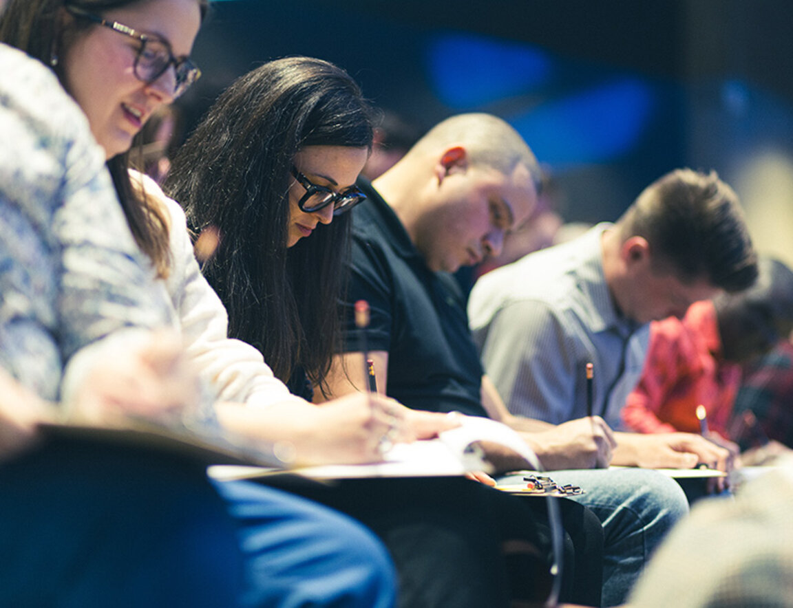 Des personnes sont assises et écrivent attentivement lors de la dictée à HEC Montréal.