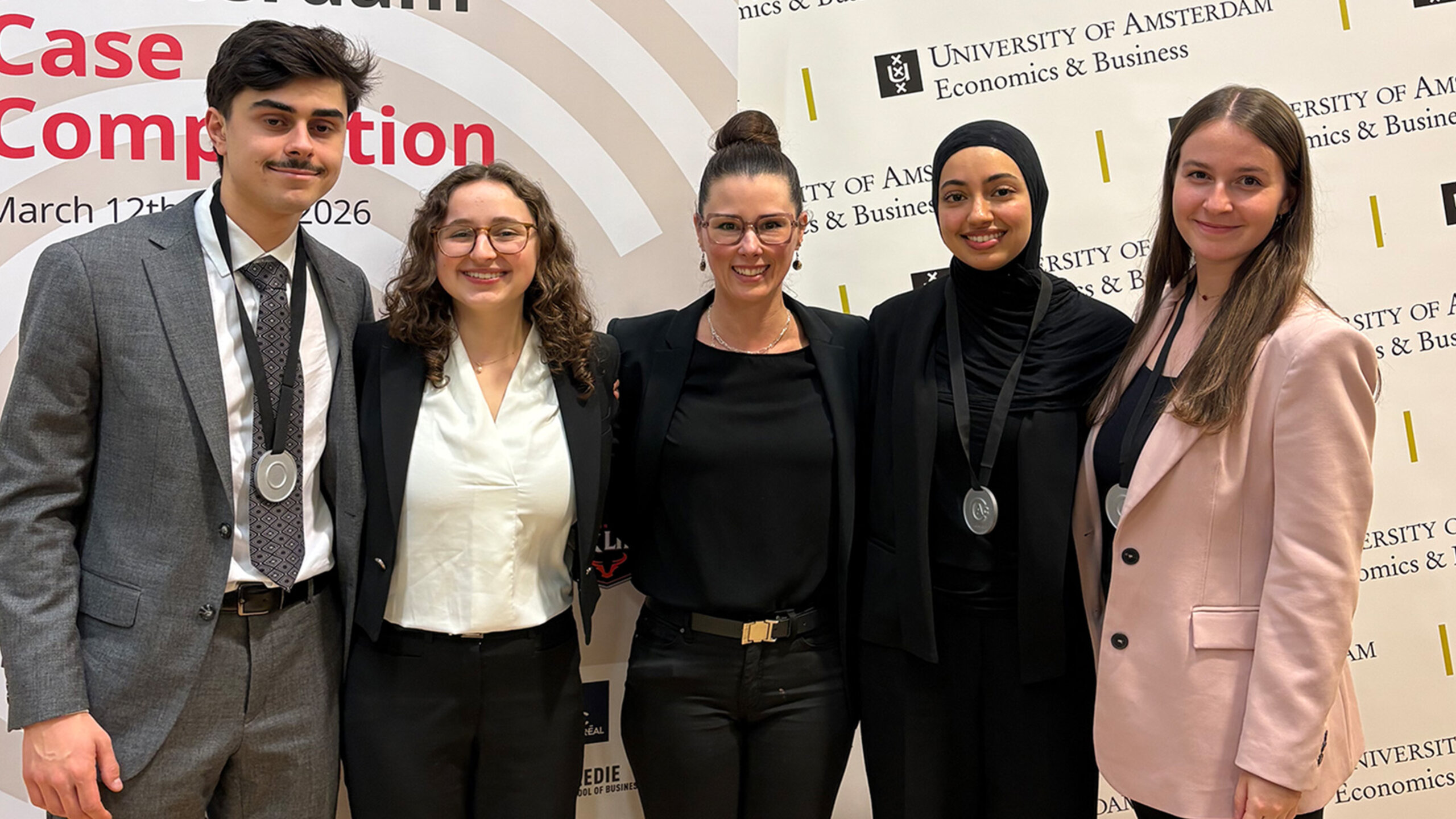 Cinq étudiantes et étudiants posent ensemble devant une vue urbaine d’Amsterdam.