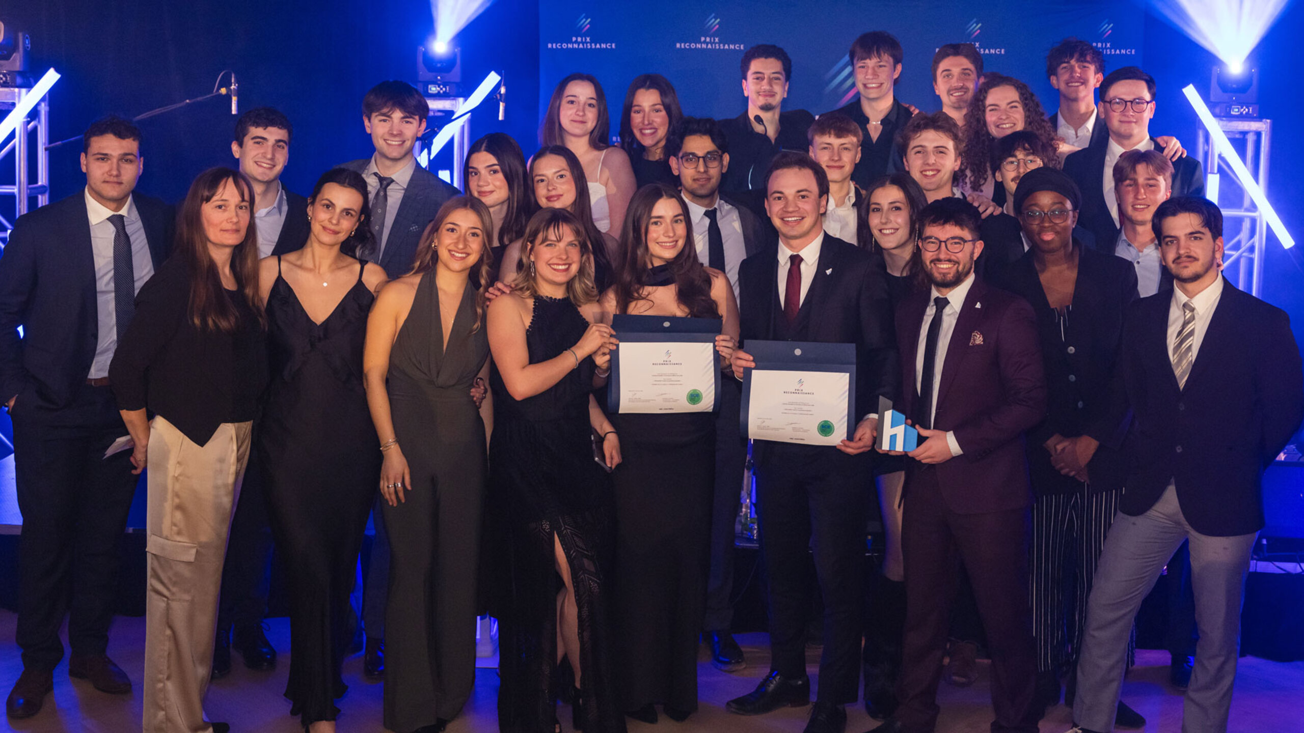 Groupe de lauréates et lauréats posant ensemble lors de la soirée du Gala des Prix reconnaissance, sur une scène éclairée, tenant des certificats et des trophées.