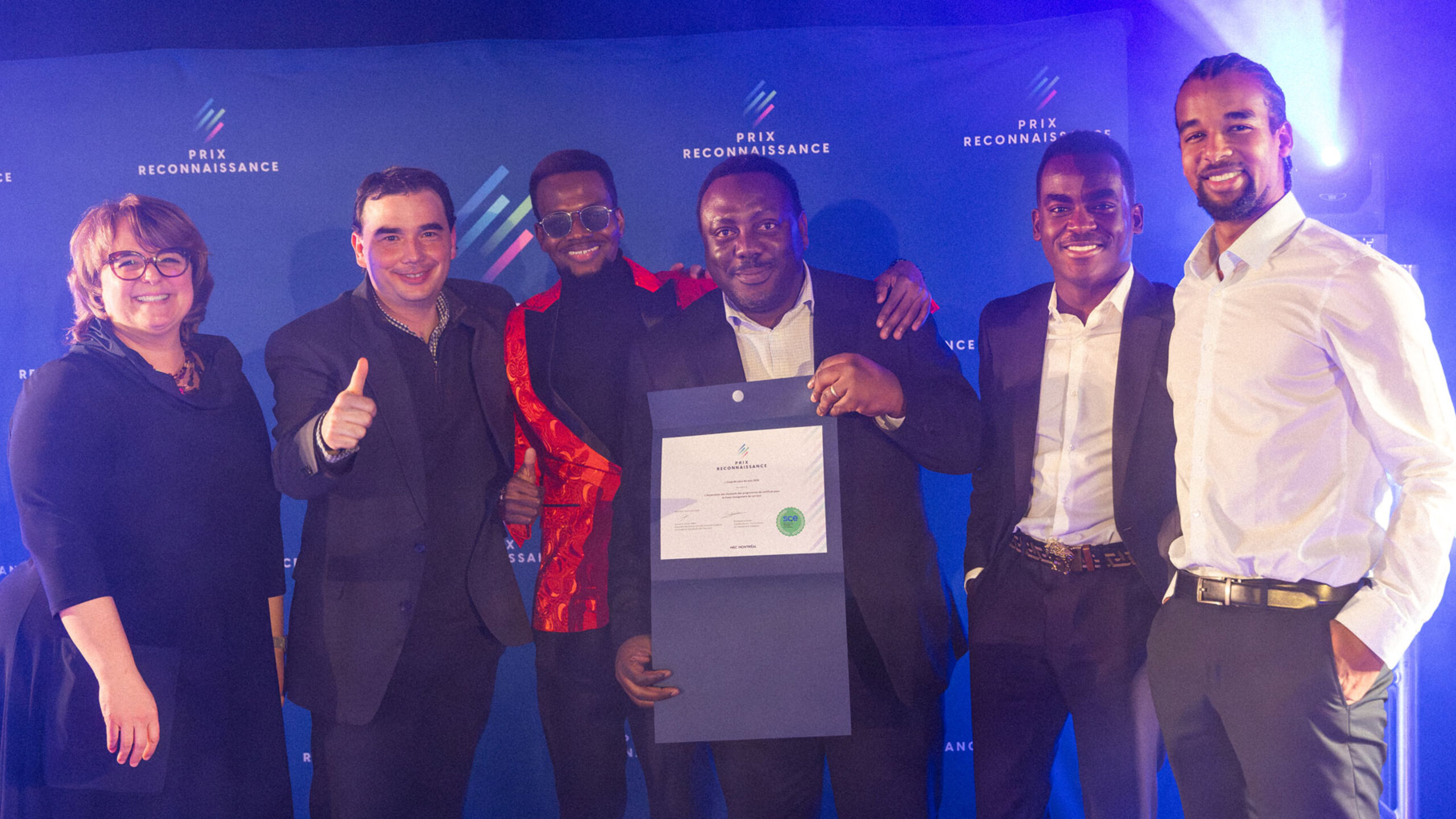 Groupe de lauréates et lauréats posant ensemble lors de la soirée du Gala des Prix reconnaissance, sur une scène éclairée, tenant des certificats et des trophées.