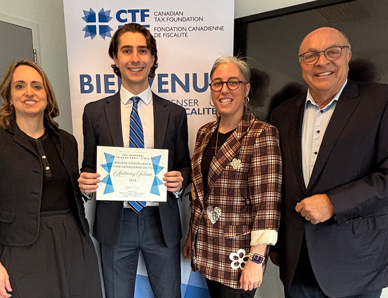 Le diplômé Anthony Tahan tenant un certificat, entouré de trois personnes, devant une bannière de la Fondation canadienne de fiscalité. 