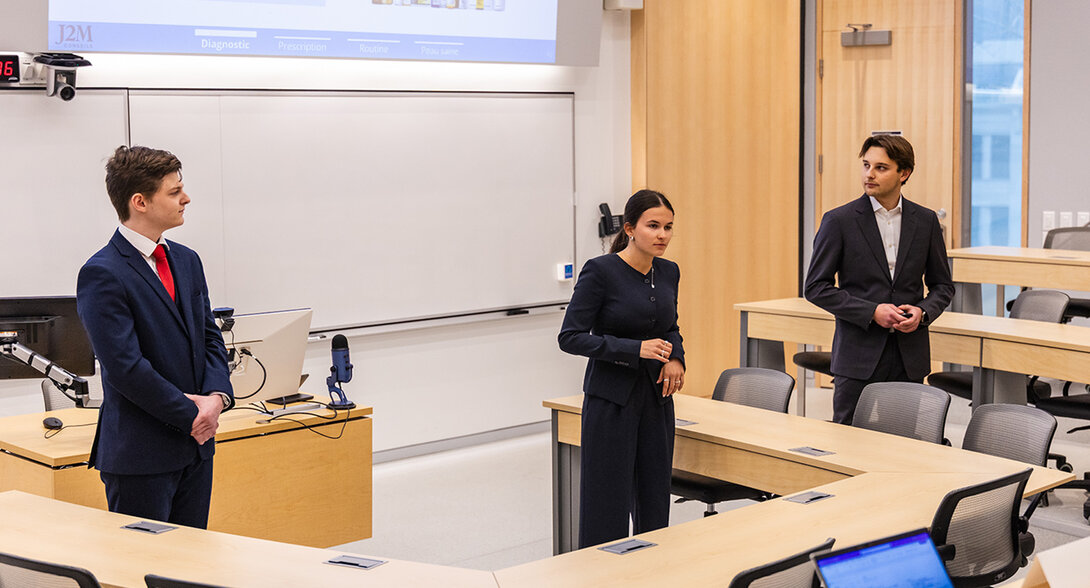 Three people are standing in front of a classroom at HEC Montréal, giving a presentation.