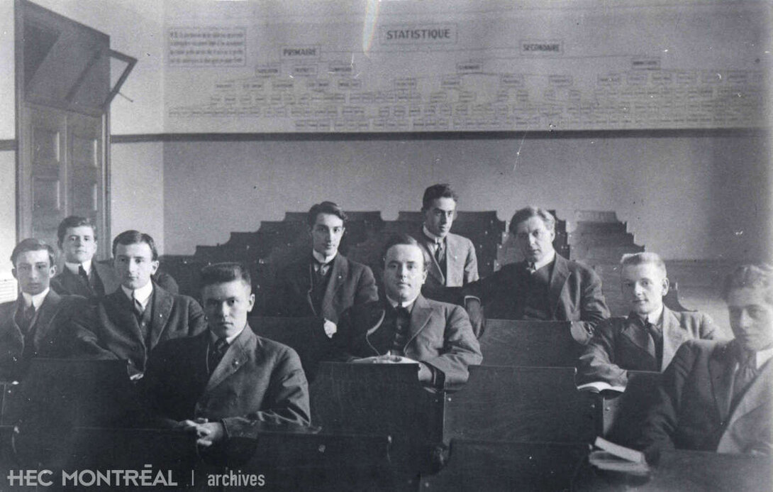   Description : Édouard Montpetit et les étudiants de la troisième promotion de HEC dans une salle de classe. Date : 1915 Crédit photo : Photographe inconnu Cote archivistique : P005/XPH,0011
