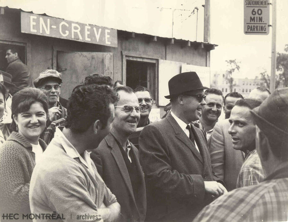   Description : Le maire de Saint-Jérôme rend visite aux ouvriers en grève de l'usine Regent Knitting Mills Ltd. Date : 1963 Crédit photo : Photographe inconnu Cote archivistique : P051/XPH-0026
